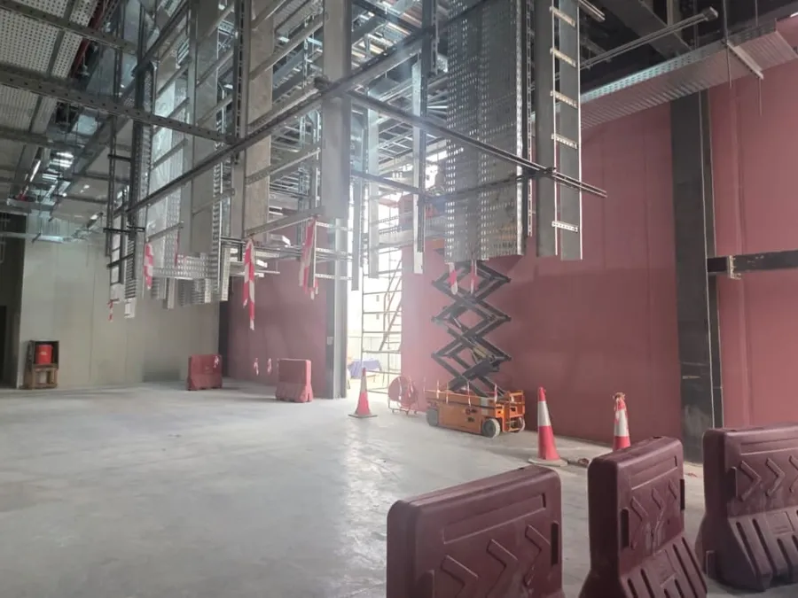 Gypsum board walls in a double-height data center hall beneath the cable tray installation